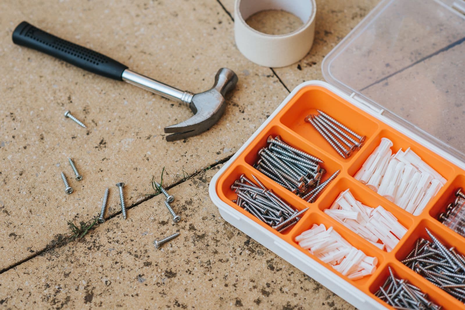 Sorted repair tools and screws laid out before a handyman visit
